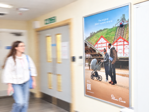 Image of a poster advert in hospital for Silver Cross with person walking past