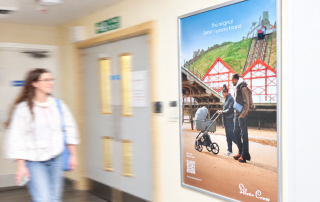 Image of a poster advert in hospital for Silver Cross with person walking past